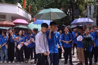 Tình nguyện viên hỗ trợ che ô cho thí sinh sau khi hoàn thành bài thi.