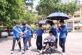 Tình nguyện viên tại điểm thi Trường THPT Nhân Chính hỗ trợ thí sinh bị gãy chân lên phòng thi.