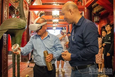 Khách du lịch thích thú khi được trải nghiệm hệ thống thực tế ảo tại di tích Văn Miếu-Quốc Tử Giám. (Ảnh: HÀ NAM)