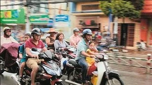 Phụ huynh chở hai cháu không đội mũ bảo hiểm trên đường Quang Trung.