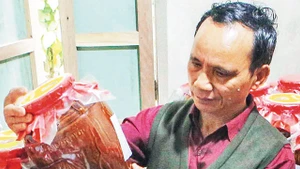 Già làng Lê Văn Nghĩa bên sản phẩm tâm huyết. Ảnh: TRẦN LÊ LÂM