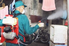 Cán bộ y tế phun hóa chất phòng chống bệnh sốt xuất huyết tại các hộ gia đình ở Hà Nội.