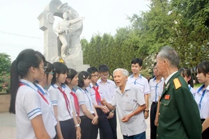 Các cháu học sinh và các cựu chiến binh mặt trận 23-10 bên tượng đài Võ Văn Ký. (Ảnh: XUÂN THÀNH)