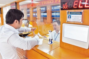 Giải quyết thủ tục hành chính cho người dân tại Bộ phận một cửa UBND quận Long Biên. Ảnh: MINH HÀ