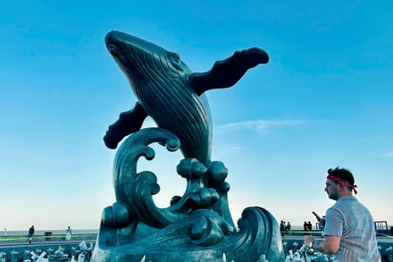 Du khách nước ngoài bên tượng Cá Ông