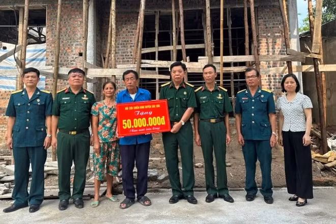 Cựu chiến binh Phạm Văn Lượng (đứng giữa) nhận hỗ trợ xây nhà mới. (Ảnh: NGỌC LAN)