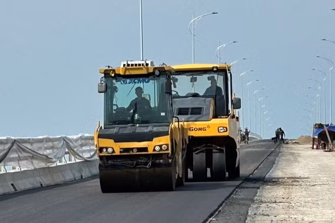 Thi công trải thảm bê-tông nhựa trên cây cầu vượt sông Hồng thuộc dự án đường bộ ven biển tỉnh Hưng Yên.