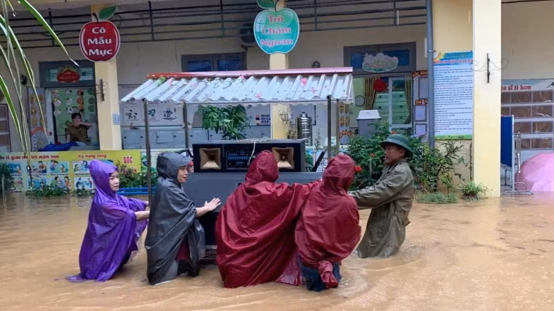 Giáo viên và lực lượng tại chỗ di chuyển đồ dùng học tập ra khỏi vùng ngập tại trường Tiểu học Sông Cầu. (Ảnh: KHÁNH LINH)