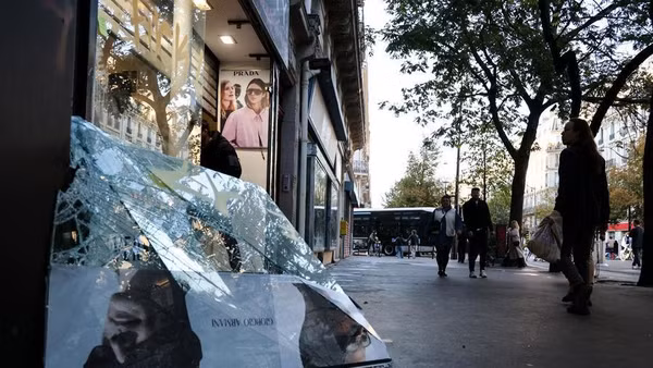 Người dân đi ngang qua một cửa hàng bị hư hại trong một cuộc biểu tình tại Paris, Pháp, ngày 18/10/2026. (Ảnh: XINHUA)
