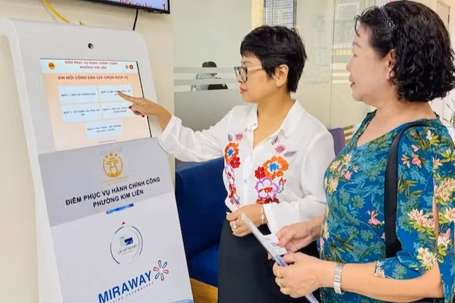 Công chức tại Điểm tiếp nhận, phục vụ hành chính công phường Kim Liên hướng dẫn người dân lấy số để thực hiện các thủ tục hành chính. (Ảnh: KHÁNH HUY)