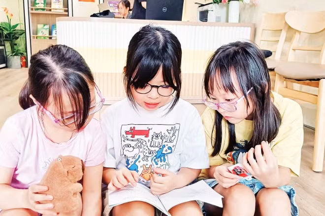 Các em nhỏ đọc sách để chuẩn bị cho cuộc thi trực tuyến. (Ảnh: MAI LỮ)