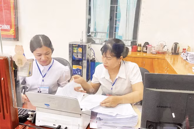 Đồng chí Phạm Thị Thúy (bên phải) cùng đồng nghiệp ở lại sau giờ làm việc tiếp tục nghiên cứu hồ sơ giúp nhân dân hoàn thành các thủ tục hành chính tại Trung tâm Phục vụ hành chính công.