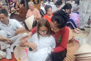 Nghệ nhân làng Chuông hướng dẫn du khách trải nghiệm các công đoạn làm nón tại không gian học tập cộng đồng ở đình làng Chuông.