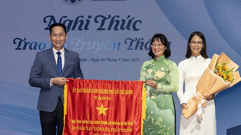 Phó Chủ tịch Ủy ban nhân dân Thành phố Hồ Chí Minh Trần Thị Diệu Thúy trao Cờ Truyền thống của Ủy ban nhân dân Thành phố cho đại diện Bảo tàng Chứng tích Chiến tranh. (Ảnh: Quốc Thanh)
