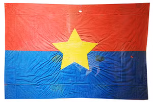 Cờ Mặt trận do nữ tù chính trị Côn Đảo may và thêu khi hay tin Hiệp định Paris ký kết. Lá cờ thấm máu tù chính trị được treo trước cửa dinh chúa đảo đúng ngày 1/5/1975.