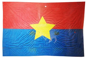 Cờ Mặt trận do nữ tù chính trị Côn Đảo may và thêu khi hay tin Hiệp định Paris ký kết. Lá cờ thấm máu tù chính trị được treo trước cửa dinh chúa đảo đúng ngày 1/5/1975.