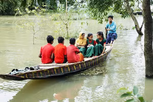 Trẻ em Bangladesh chèo thuyền qua vùng ngập lụt để đến trường. Ảnh: UNICEF