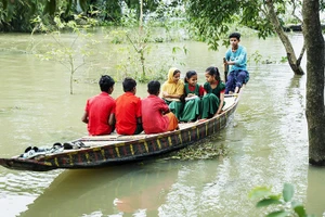 Trẻ em Bangladesh chèo thuyền qua vùng ngập lụt để đến trường. Ảnh: UNICEF