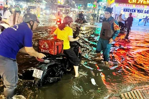 Lực lượng xung kích trợ giúp người dân di chuyển khi triều cường dâng cao.