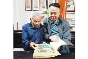 Nghệ nhân Nguyễn Đăng Chế giới thiệu với tác giả bài viết bộ sưu tập tranh dân gian Đông Hồ.