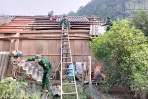 Cán bộ, chiến sĩ Đồn Biên phòng Chiềng Sơn giúp hộ gia đình anh Lò Văn Thực lợp lại mái nhà. (Ảnh: QUÀNG HÙNG)