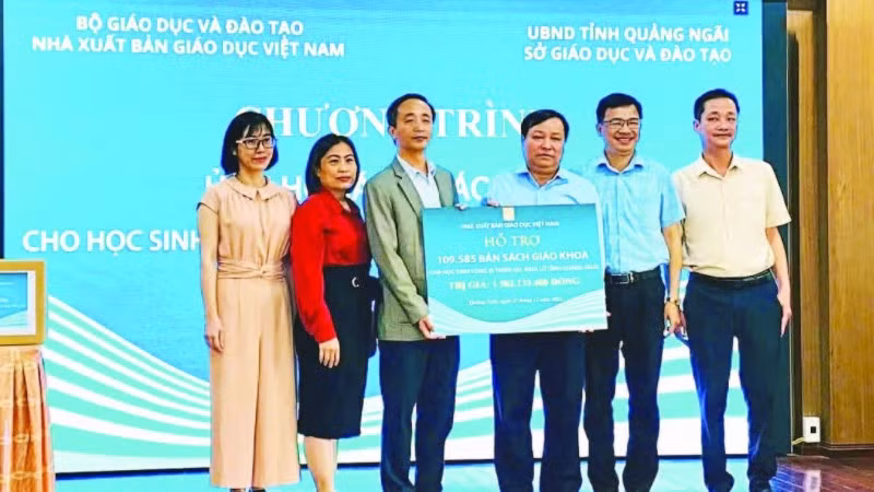 Đại diện Nhà xuất bản Giáo dục Việt Nam trao tặng sách giáo khoa cho học sinh vùng lũ Quảng Ngãi. (Ảnh ÁI KIỀU)