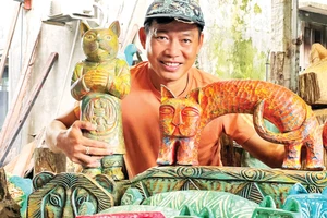 Anh Lê Ngọc Thuận bên một số tác phẩm từ củi lũ. (Ảnh: NVCC)