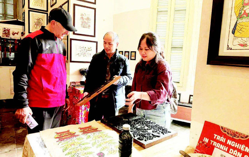 Võ Ca Dao hướng dẫn cho du khách nước ngoài trải nghiệm in tranh mộc bản.