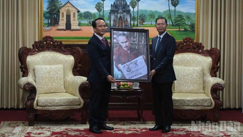 Phó Bí thư Thường trực Thành ủy Đà Nẵng Nguyễn Đình Vĩnh trao tặng bức ảnh Bác Hồ đọc Báo Nhân Dân cho lãnh đạo tỉnh Savannakhet. (Ảnh: ANH ĐÀO)