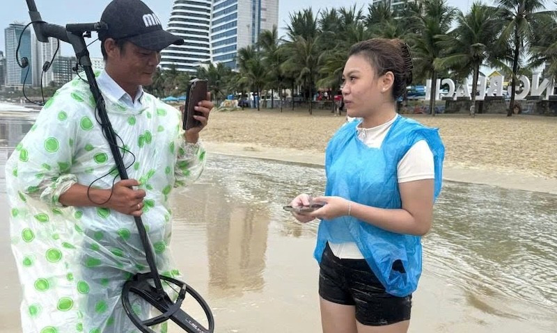 Nữ du khách nhận lại tài sản bị sóng biển nhấn chìm sau nỗ lực hỗ trợ, tìm kiếm của các nhân viên Ban Quản lý bán đảo Sơn Trà và các bãi biển du lịch Đà Nẵng. (Ảnh: HG)