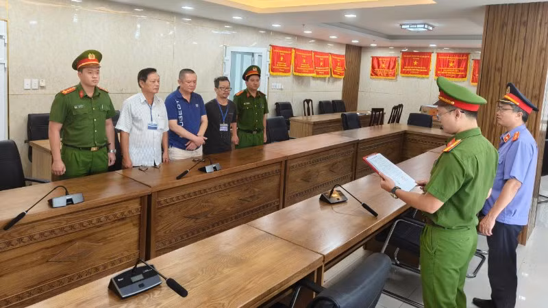 Cơ quan điều tra tống đạt các quyết định khởi tố đối với ba bị can. (Ảnh: Công an cung cấp)