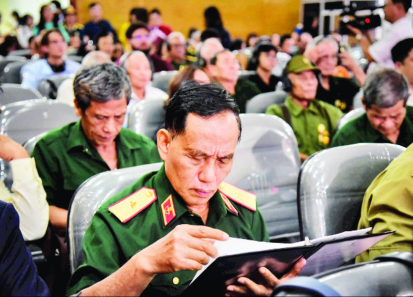 Thiếu tướng Trịnh Xuân Chuyền đọc những dòng chữ trong hồ sơ của đồng đội được trao trả. (Ảnh GIA KHÁNH)