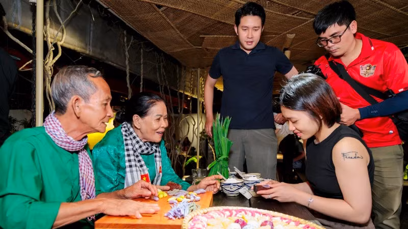 Vợ chồng nghệ nhân Trương Thị Chiều hướng dẫn du khách trải nghiệm làm bánh dân gian.