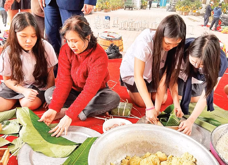 Các em học sinh trải nghiệm gói bánh chưng cùng hội viên Câu lạc bộ Liên thế hệ tự giúp nhau phường Khương Đình (thành phố Hà Nội).