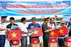 Cảnh sát biển trao cờ Tổ quốc và phát tờ rơi tuyên truyền cho ngư dân tại xã Thạnh An.
