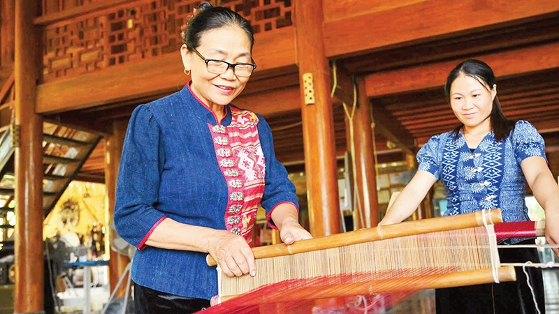 Nghệ nhân Sầm Thị Bích ( người bên trái) trình diễn kỹ thuật dệt thổ cẩm. (Ảnh THÀNH CƯỜNG)