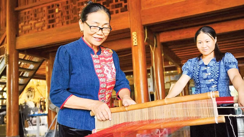 Nghệ nhân Sầm Thị Bích ( người bên trái) trình diễn kỹ thuật dệt thổ cẩm. (Ảnh THÀNH CƯỜNG)