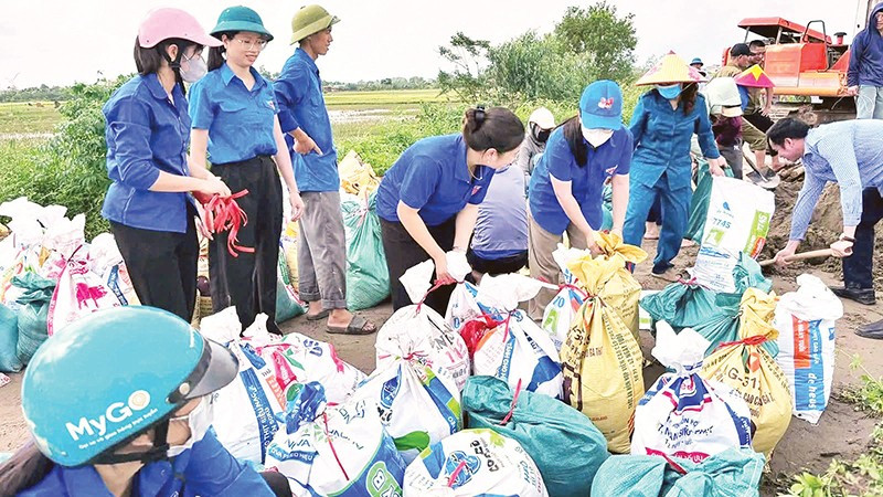 Đoàn viên, thanh niên tình nguyện xã Nam Phù cùng lực lượng chức năng và người dân đắp bao tải cát chắn nước từ sông Hồng tràn vào các thôn.