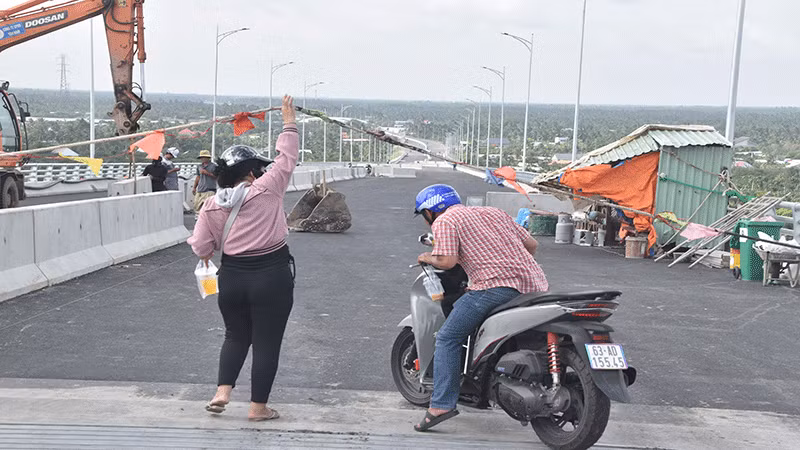 Người dân nâng dây để đi qua cầu Rạch Miễu 2.