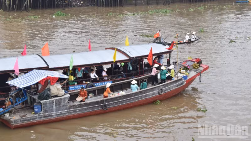 Tái hiện cảnh mua bán giữa thương lái và khách du lịch tại chợ nổi Cái Bè sáng 4/12/2025.