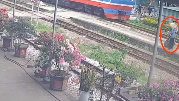Cụ bà được công nhân đường sắt Dương Văn Kiên cứu chỉ 2 giây trước khi đoàn tàu chạy qua. (Ảnh cắt từ camera ghi lại)