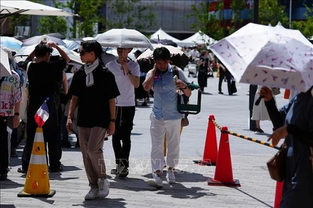 Người dân di chuyển trên đường phố dưới trời nắng nóng tại Osaka, Nhật Bản. (Ảnh: TTXVN)