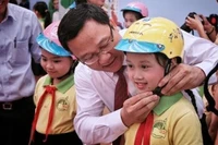 Đồng chí Khuất Việt Hùng, Phó Chủ tịch chuyên trách Ủy ban ATGT quốc gia đội mũ bảo hiểm cho trẻ em. (Ảnh: Ủy ban ATGT quốc gia)