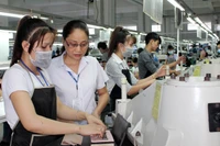 Đảng viên Nguyễn Thị Hương (thứ hai từ trái sang) hướng dẫn công nhân trong dây chuyền sản xuất.