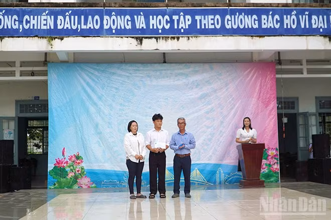Em Trần Lê Nguyễn nhận tiền hỗ trợ của Quỹ xã hội Cỏ May tại sân trường.