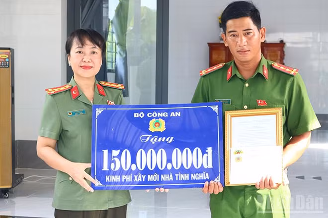 Đại tá Võ Thị Hoài Ngọc, Phó Giám đốc Công an tỉnh Đồng Tháp trao bảng tượng trưng kinh phí xây mới nhà tình nghĩa do Bộ Công an hỗ trợ tặng Đại úy Trần Minh Giàu. (Ảnh: PHƯỚC THANH)