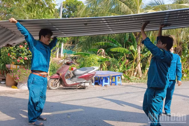 Lực lượng chức năng xã Tân Long giúp người dân lợp lại mái nhà do ảnh hưởng dông lốc.