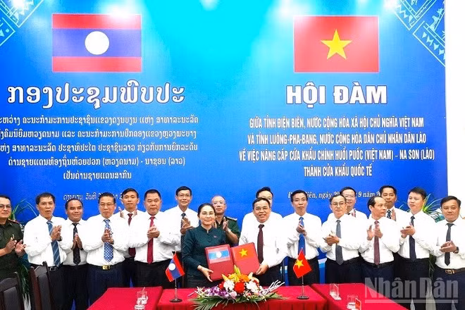 Hai đồng chí Trưởng đoàn trao biên bản hội đàm ký kết về việc thống nhất báo cáo cấp có thẩm quyền nâng cấp cặp cửa khẩu chính Huổi Puốc (Việt Nam)-Na Son (Lào) thành cửa khẩu quốc tế. (Ảnh: LÊ LAN)