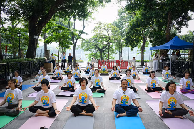 Các đại biểu, cùng đông đảo phóng viên, biên tập viên, người lao động Báo Nhân Dân tham gia màn đồng diễn Yoga tại khuôn viên trụ sở Báo Nhân Dân tại Hà Nội. (Ảnh: BẢO LONG)