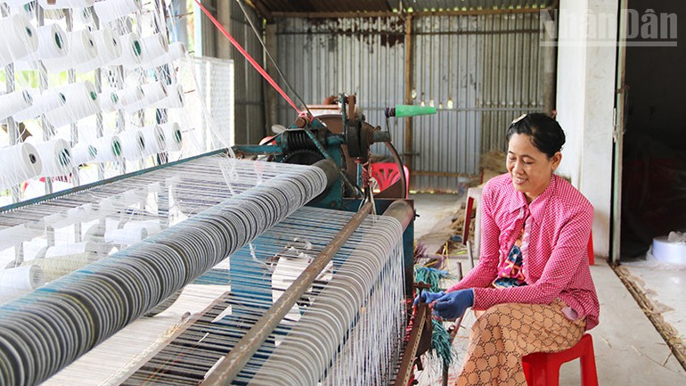 Bà Nguyễn Thị Minh Trang, chủ cơ sở dệt chiếu ấp Ðức Mỹ, xã Nhị Long đang dệt chiếu bằng máy dệt bán tự động. ndo_tr_a2.jpg